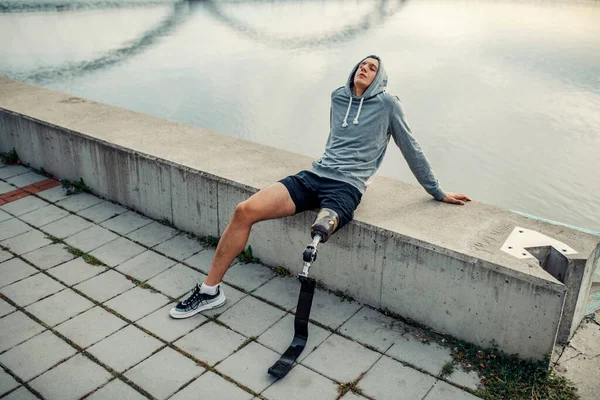 Yapay Bacaklı Rahat Bir Sporcu Rıhtımda Tek Başına Oturuyor Dinleniyor — Stok fotoğraf