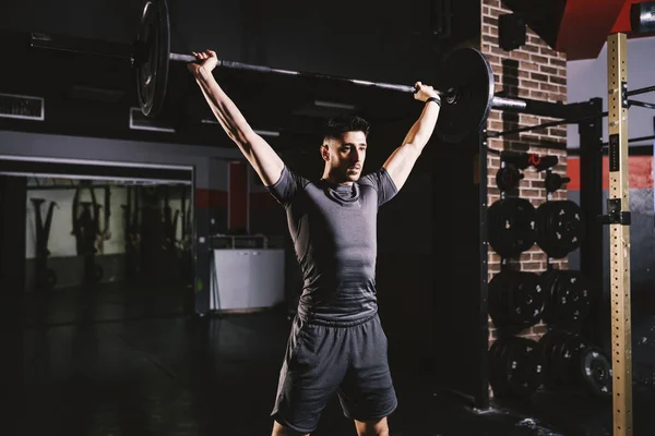 一个强壮的男人在健身房举重和做二头肌运动 — 图库照片