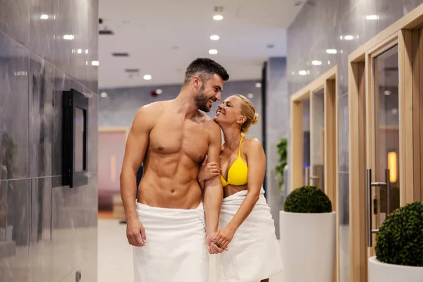 スパで幸せなカップル タオルを着た素敵な魅力的なカップルが手を取り合ってスパの中心部を歩いています リゾートでロマンチックな週末 — ストック写真