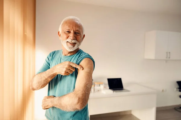 Счастливый Пожилой Человек Кабинете Врача Указывает Вакцинированное Плечо Иммунизация Вакцинация — стоковое фото