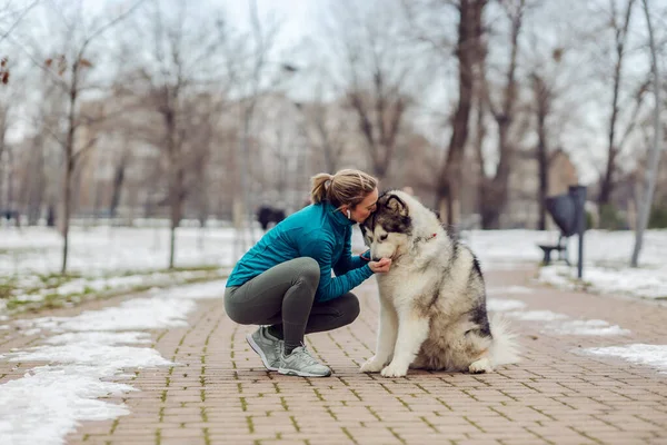 Deportiva Besando Perro Abrazándolo Mientras Agacha Parque Clima Nevado Mascotas — Foto de Stock