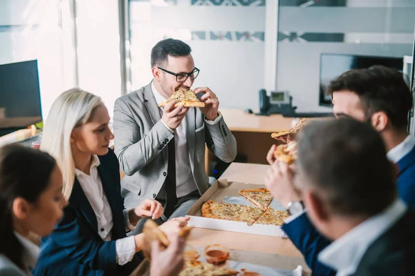 会議室での昼食にピザを食べるビジネスマンのグループ — ストック写真