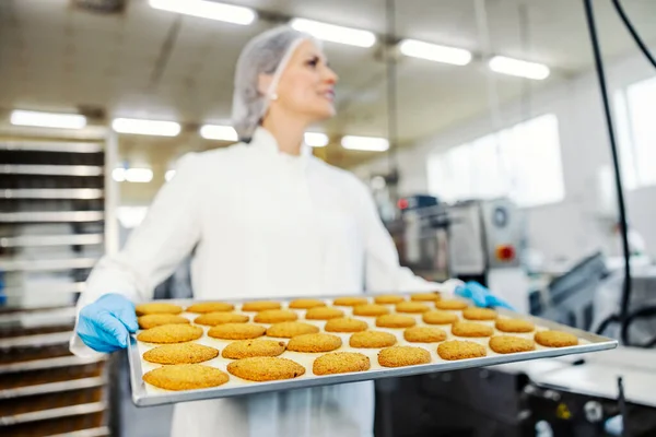 クッキーとトレイを保持する女性食品工場労働者 — ストック写真