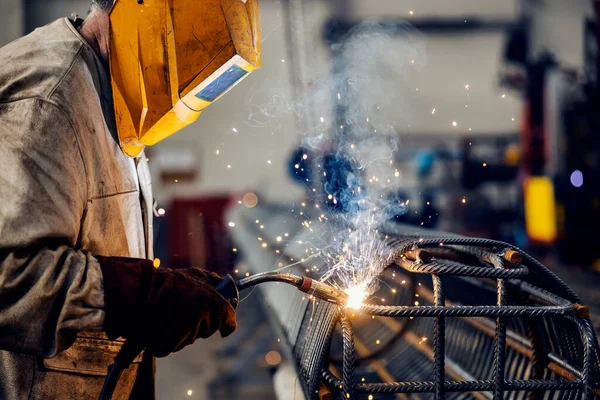 A steel, metal and heavy industry factory worker manufacturing metal construction wit welder.