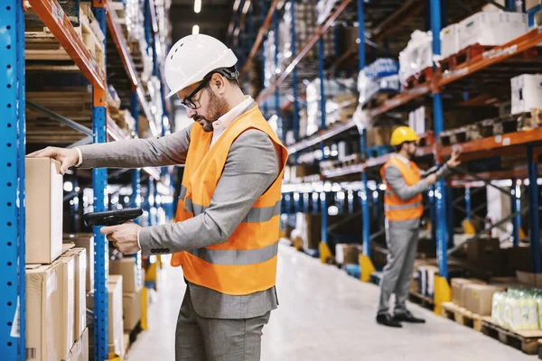 Supervisors scanning bar and qr codes on boxes at storage.