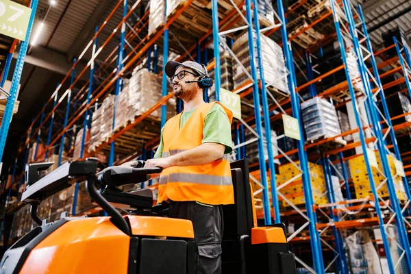 A worker with voice picking headset driving orders for shipping on forklift at storage.