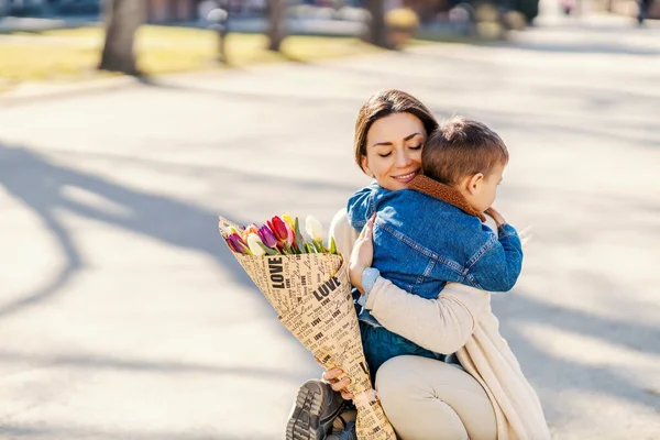 Menino Abraçando Mãe Com Flores Dia Mãe — Fotografia de Stock