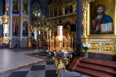Rus Ortodoks katedralindeki ikonların arka planında kilise mumları