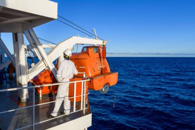 Turuncuyu tamamen kapalı bir filikayla suya indirmek. Tatbikatı terk edin. Filika eğitimi. Tatbikatta bir adam var..