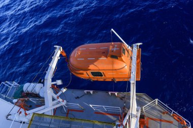 Turuncuyu tamamen kapalı bir filikayla suya indirmek. Tatbikatı terk edin. Filika eğitimi. Tatbikatta bir adam var..