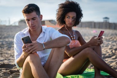 Güvenilmez kızartılmış kız arkadaşının akıllı telefonu akıllı telefonları ellerinde akıllı telefonları olan kıskanç koca karısını cep telefonundan izleyen adam sevgilisinin telefonuna bakıyor.