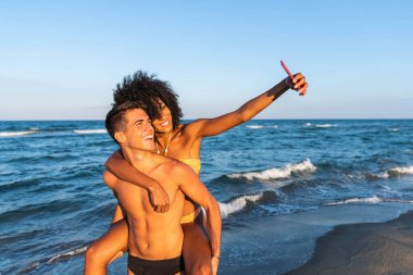 İnanılmaz tropikal sahilde eğlenen genç çiftlerin eğlenceli oto portresi mutlu seyahat eden çiftin selfie çekmesi güneşli yaz renkleri romantik bir ruh hali sahilde mutlu bir çift - sırt sırta gezintisi