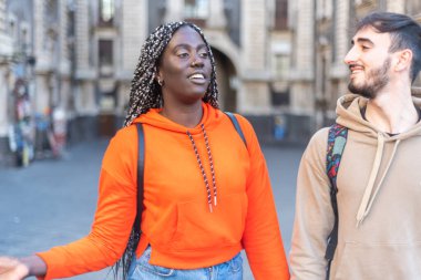 Birlikte olmaktan mutluyum - çok ırklı genç bir çiftin el ele tutuşmasını görmek - gülümseyerek caddede yürürken 