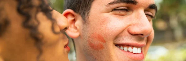 Multiethnic Young people kiss on cheek with lipstick  portrait of two people kissing on cheek  woman kissing her boyfriend -  happy loving woman kissing boy friend on cheek
