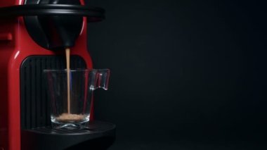 Kahve makinesiyle kahve makinesini şeffaf bardağa çevirme işlemi - kahve makinesinden çıkan espresso kahvesi - siyah arka planda 