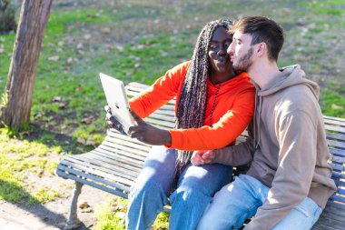 Karışık ırktan genç bir çift akıllı telefonuyla selfie çekiyor. Mutlu, etnik çeşitlilikte bir çift şehirde fotoğraf çekiyor. 