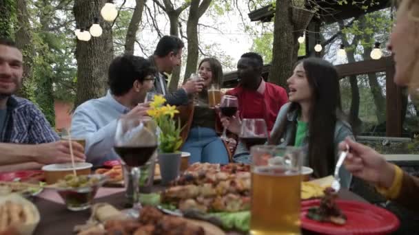 多种族的人在家里的阳台上享用红酒 啤酒和鸡尾酒 多种族的朋友们在阳台上吃饭 快乐的家庭在后院享用开胃酒和酒会 — 图库视频影像