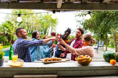 Happy multiethnic young people toasting at kiosk bar of pool