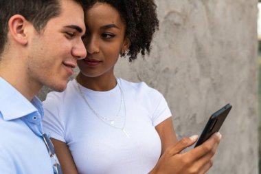 Smiling young couple using mobile phone  Happy young people looking smartphone  smiling woman and man look cellphone 
