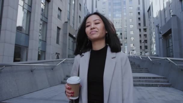 Νεαρή ενήλικη Ασιάτισσα επιχειρηματίας που περπατάει από το γραφείο με ένα φλιτζάνι καφέ σε αργή κίνηση — Αρχείο Βίντεο