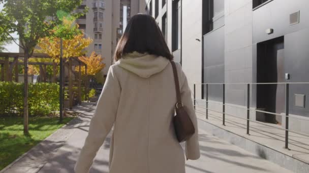 现代的成年女子在城市街道上的金黄色的树木中漫步 — 图库视频影像