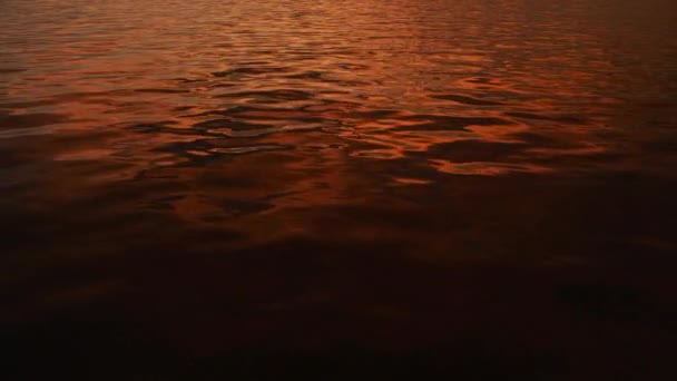 Superficie de agua de un río en una puesta de sol con reflejos naranjas brillantes fuera en verano — Vídeos de Stock