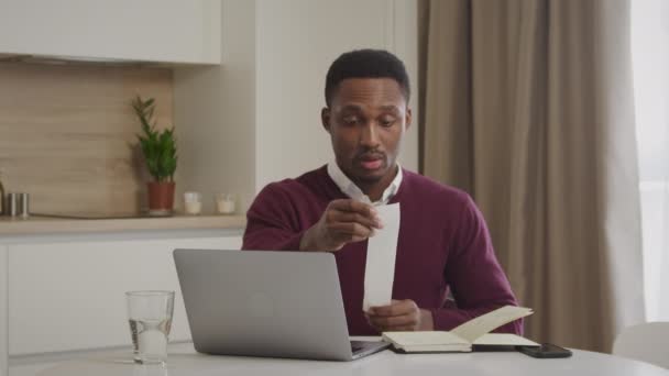 Genç Afrikalı Amerikalı adam faturalarını kontrol ediyor ve ev harcamalarını yönetiyor. — Stok video