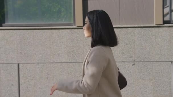 Vista lateral de una mujer de negocios asiática adulta caminando en la ciudad — Vídeos de Stock