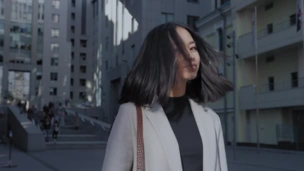 年轻的亚洲女人摇着头发，看着城市里的相机 — 图库视频影像