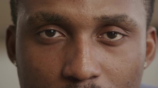 Крайне близко к неузнаваемому африканскому чёрному мужчине, открывающему глаза и смотрящему прямо в камеру — стоковое видео