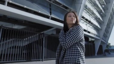 Genç Asyalı bir kadının şehir merkezinde kendine güvenen yürüyüşü