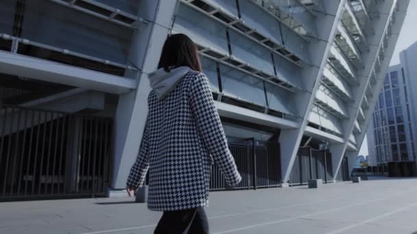 Pivotaje disparo de un joven adulto asiático mujer caminando en un urbano ubicación — Vídeo de stock