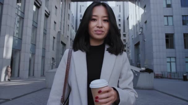 Πορτρέτο μιας νεαρής ενήλικης ασιάτισσας επιχειρηματία που περπατάει από το γραφείο με ένα φλιτζάνι καφέ σε αργή κίνηση — Αρχείο Βίντεο