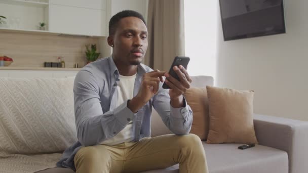 Портрет молодого афроамериканця, який друкує на своєму смартфоні — стокове відео
