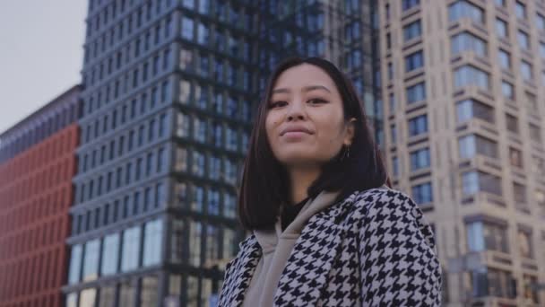 Low-angle portret van een jonge volwassen aziatische vrouw in het centrum van de wijk — Stockvideo