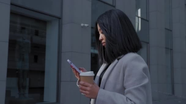 Schwenkbares Porträt einer asiatischen Frau, die ein Smartphone in einem Businesscenter hält und wegschaut — Stockvideo