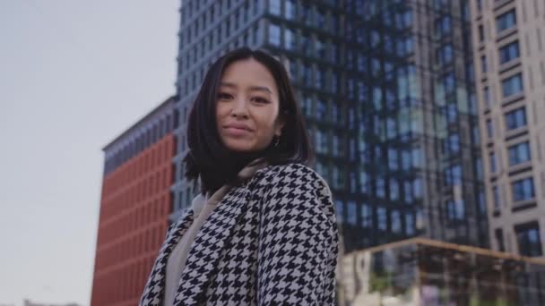 Low-angle portret van een jonge volwassen aziatische vrouw in het centrum van de wijk — Stockvideo