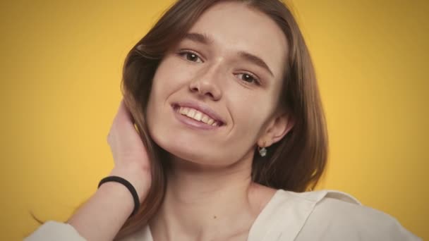 Retrato de una mujer caucásica de 20 años sonriendo a la cámara sobre un fondo amarillo brillante — Vídeo de stock