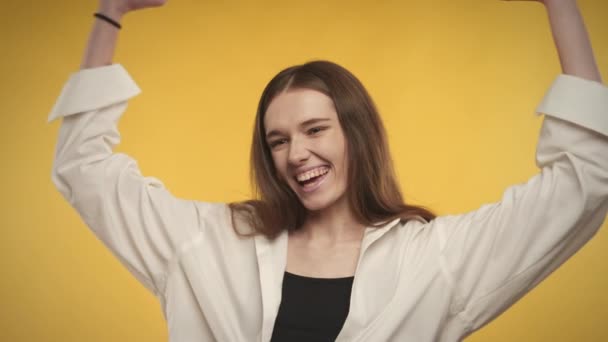 Joven mujer caucásica adulta está celebrando un logro sobre un fondo amarillo brillante — Vídeos de Stock