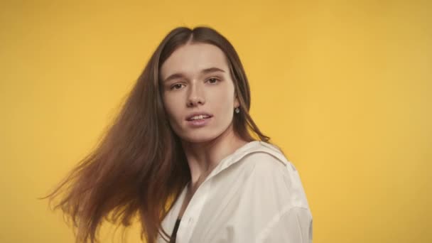 Mladá dospělá běloška žena se otáčí a třese vlasy na jasně žlutém pozadí — Stock video