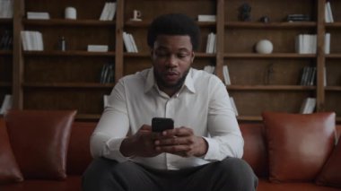 Genç Afrikalı Amerikalı adam akıllı telefonuyla alışveriş yaparken şaşırdı.