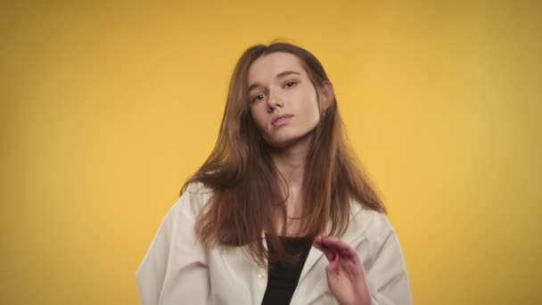 Joven mujer caucásica adulta posando en cámara lenta sobre un fondo amarillo brillante — Vídeos de Stock