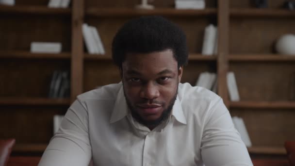 Ung vuxen afrikansk amerikansk affärsman lyfter upp huvudet och tittar på kameran — Stockvideo