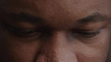 Afro-Amerikalı bir adamın keder içinde yukarıdan bakan gözünün aşırı yakın çekimi.