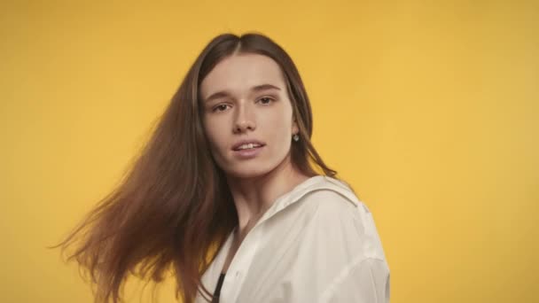 Fiatal felnőtt kaukázusi nő fordul és rázza a haját fényes sárga háttér — Stock videók