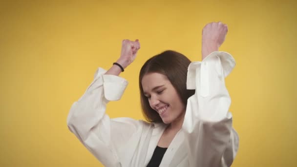 Joven mujer caucásica adulta está celebrando un logro sobre un fondo amarillo brillante — Vídeos de Stock