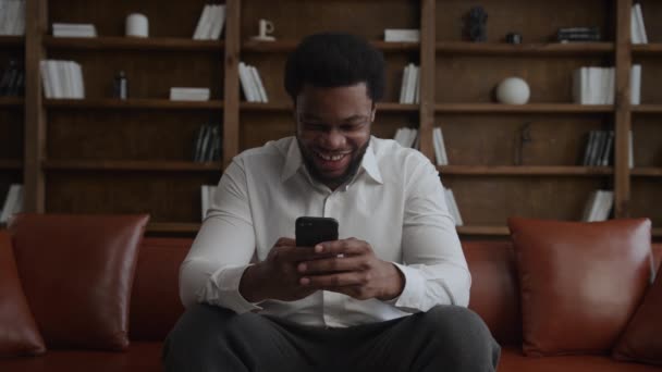 Joven hombre adulto riendo con un smartphone en sus manos — Vídeo de stock