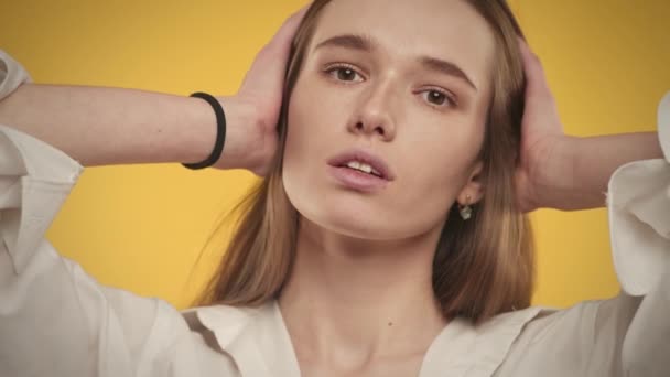 Retrato de una mujer caucásica de 20 años sonriendo a la cámara sobre un fondo amarillo brillante — Vídeos de Stock