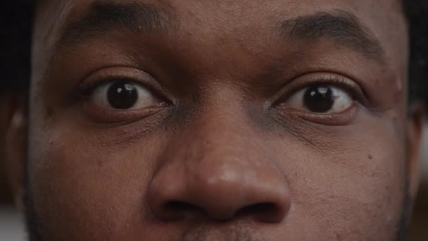 Extremt närbild av en överraskad afrikansk-amerikansk man ögon får goda nyheter — Stockvideo