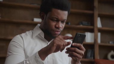 Ofisteki akıllı telefonunda gezinen yetişkin bir adamın portresi.